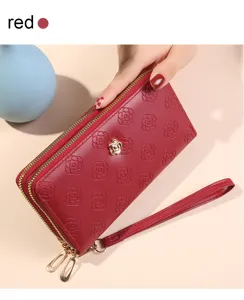 Détail de portefeuille long rouge avec motif de fleurs de camélia gaufré et double zip.
