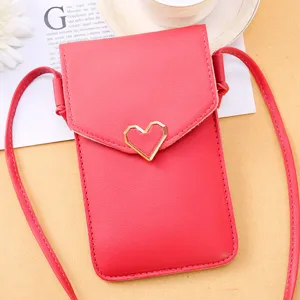 Red cross-body phone bag detail featuring a cute gold heart clasp and fine leather texture.