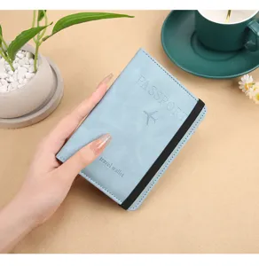 Close-up detail of the PU leather passport holder with elastic band and debossed travel text.
