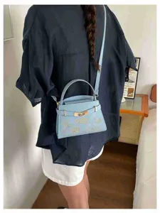 Stylish light blue women handbag with top handle and crossbody strap, elegant design.