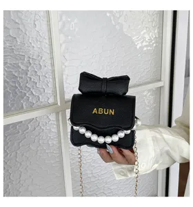 Vue rapprochée détaillée d'un mini sac à épaule noir avec nœud, perles et chaîne.