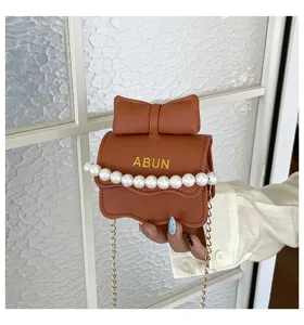 Gros-plan détaillé du sac à bandoulière en cuir marron avec perles et nœud design.
