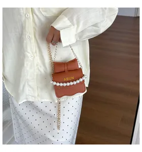 Vue détaillée du mini sac bandoulière marron avec nœud, perles et chaîne métal.
