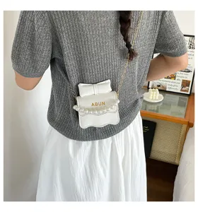 Sac bandouliere blanc avec chaine de perles, noeud et rabat ondule pour femmes automne.