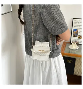 Chic sac bandoulière blanc pour femme avec détail de perles, nœud et chaîne pour le style.