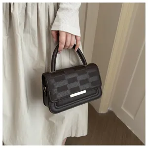 Gros plan du sac à main rétro à carreaux marron, affichant une texture texturée et du métal doré.