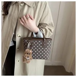 Detailaufnahme der braunen Handtasche mit weissem Muster und Plueschhund Anhänger.