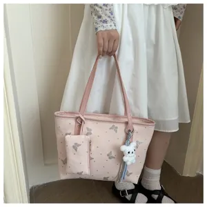 Detailed view of pink butterfly print tote bag with cute bear charm and small pouch accessory.