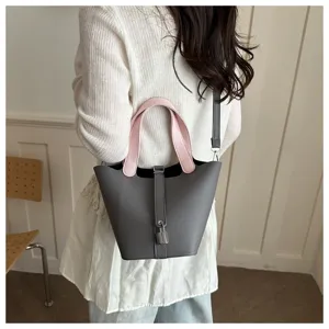 Detailed view of the chic gray bucket handbag featuring pink handles and padlock charm.