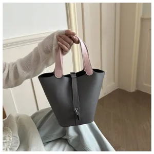Stylish grey and pink leather bucket handbag detail view, elegant minimalist design for women.