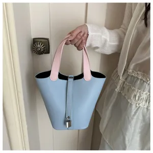 Chic light blue bucket bag with pink handles and padlock detail, stylish women shoulder bag.