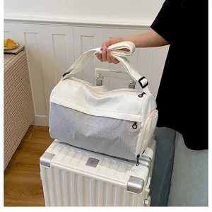 Detail view of the lightweight travel duffel bag held over a suitcase in indoor scene.