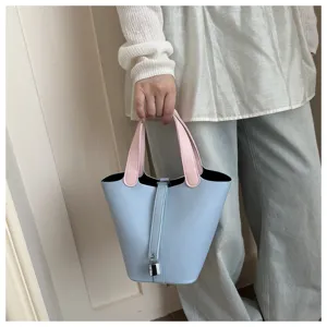 Chic light blue bucket bag with pink handles and cute lock detail for women daily style.