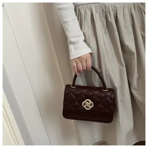 Detailaufnahme der dunkelbraunen gesteppten Handtasche mit elegantem goldenen Blumenverschluss.