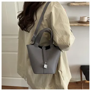 Elegant grey bucket shoulder bag with chic lock closure, stylish daily accessory for women.