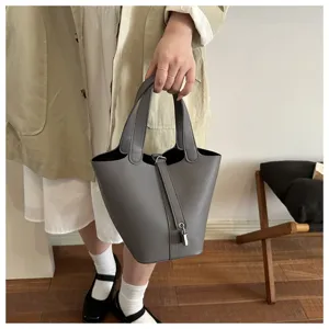Elegant grey leather bucket handbag close up detail showcasing minimalist style and secure metal lock.