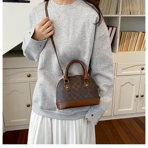 Detail view of retro brown monogram dome crossbody handbag with top handles and removable strap.