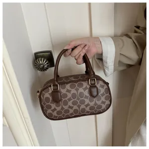 Close-up detail of retro brown monogram bowling handbag showing premium texture, stitching and metallic hardware.