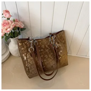 Detail shot of brown large capacity tote bag with digital number print and chain strap detail.