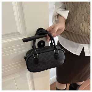 Detail view of black vintage monogram pattern handbag hanging on door handle in interior scene