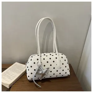 Close-up detail of white polka dot pillow shoulder bag with cute silver star charm.
