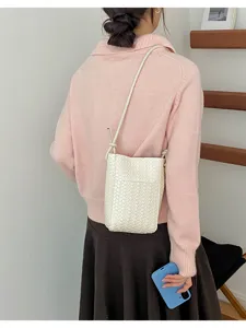 Detail shot of a stylish white woven crossbody phone bag worn by a model, casual design.