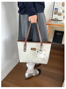 Detailed view of casual canvas tote bag with brown PU leather handles and cute plush charm.