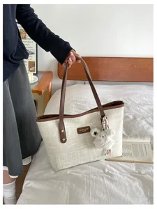 Chic canvas tote bag for women, retro casual shoulder bag with cute plush bear pendant.