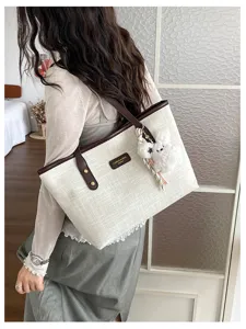Casual commuter tote bag for women, retro canvas shoulder bag with plush charm detail.