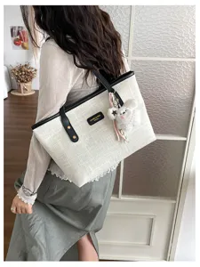 Detail view of vintage casual canvas tote bag with black leather trim and cute plush charm.