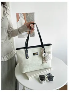 Exquisite detail of the trendy retro canvas tote bag with chic plush charm and black handles.