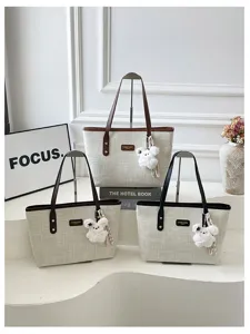 Detailed view of trendy canvas tote bag with retro leather straps and cute plush bear charm.
