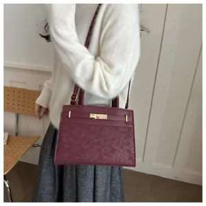 Weinrote Umhängetasche mit floralen Spitzendetails, elegantes Pendleraccessoire im Alltag.