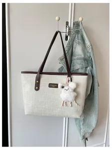 Canvas tote bag casual commuter shoulder handbag with cute plush keychain charm accessory.