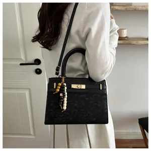 Detailansicht einer schwarzen PU-Ledertasche mit Blumenmuster und schickem Perlenanhänger.