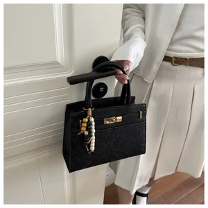Elegante schwarze Handtasche mit Blumenprägung, schickem Anhänger und Drehverschluss.