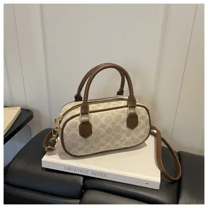 Retro monogram barrel handbag with top handle and crossbody strap, chic winter fashion.