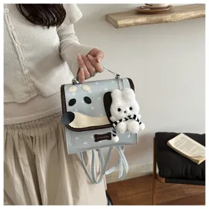 Detailed shot of a cute light blue cartoon dog backpack with a fluffy plush rabbit pendant.