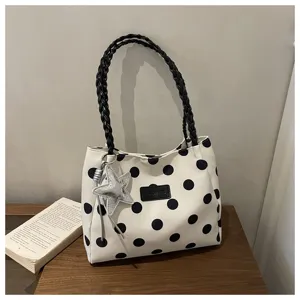 Vista dettagliata della tote in tela a pois bianchi e neri con manico intrecciato e ciondolo stella.
