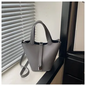 Chic grey bucket bag for women, premium leather top handle handbag with stylish lock detail.