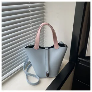 Detail view of stylish light blue bucket bag with pink contrast handles and secure lock.