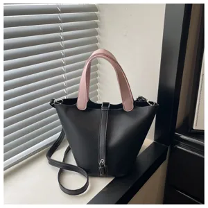 Detailed view of the stylish women bucket handbag in black with pink handles, minimalist design.