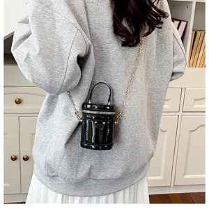 Petit sac bandoulière cylindrique en cuir verni noir avec chaîne, chic et tendance.