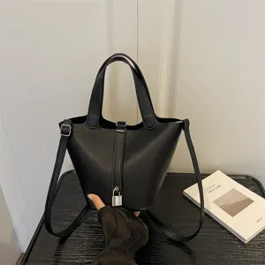 Classic black leather bucket bag featuring top handles and adjustable shoulder strap.