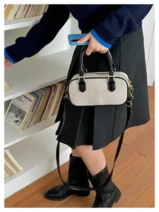 Detalle del bolso bandolera retro de lona con elegantes acabados en cuero y accesorios metálicos.