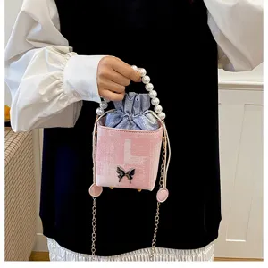 Detail of small pink box handbag with pearl handle, drawstring inner pouch, and cute butterfly.