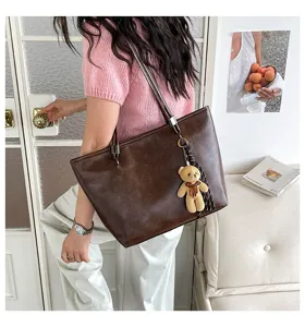 Vista dettagliata della borsa tote a spalla in pelle PU marrone da donna con ciondolo orsetto.