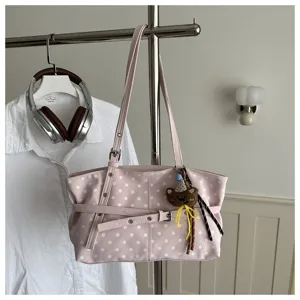Dettaglio borsa a spalla rosa a pois, shopper elegante con ciondolo orsetto e cinghia.