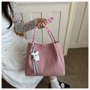 Pink houndstooth tote bag detail shot featuring braided handle and cute plush rabbit pendant.