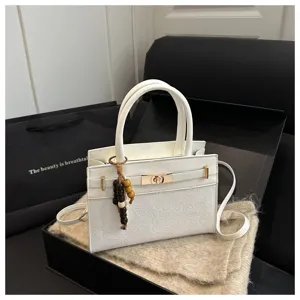 Weiße Leder-Detailansicht der Handtasche mit goldenem Drehverschluss und Perlenanhänger.